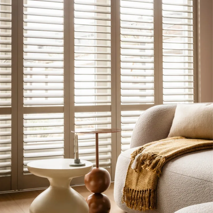 Warm kleurrijke woonkamer met lichte houtlook pvc-vloer, vloerkleed en witte shutters