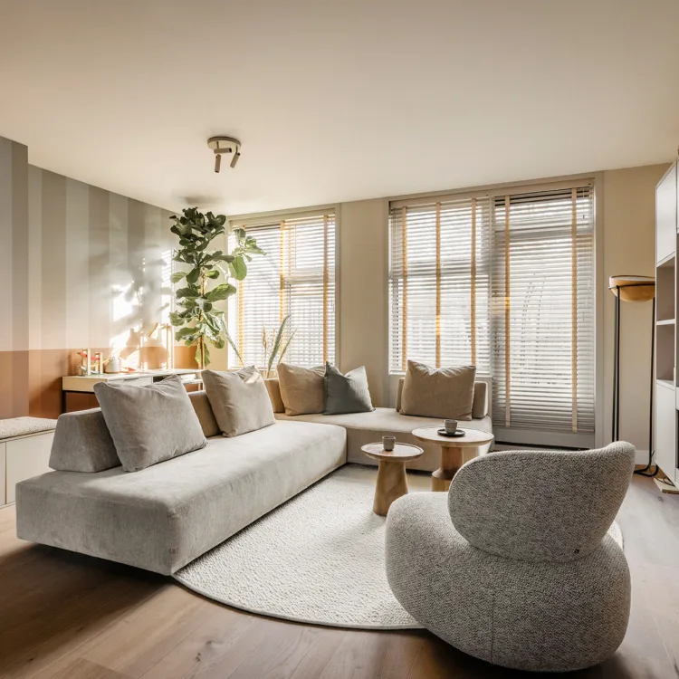 lichte woonkamer met lichte kast op maat, houten vloer en houten jaloezieën