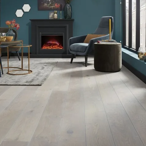 Lichte houten vloer in een sfeervolle woonkamer met blauwe muren en een open haard.