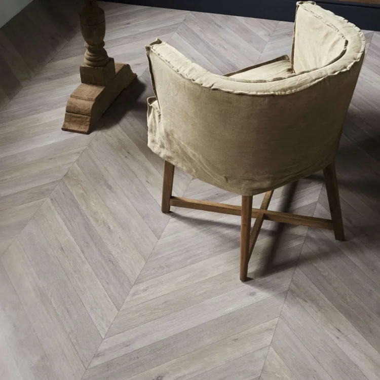 Laminaatvloer in Hongaarse punt in een eetkamer met ronde houten tafel en gestoffeerde stoel.