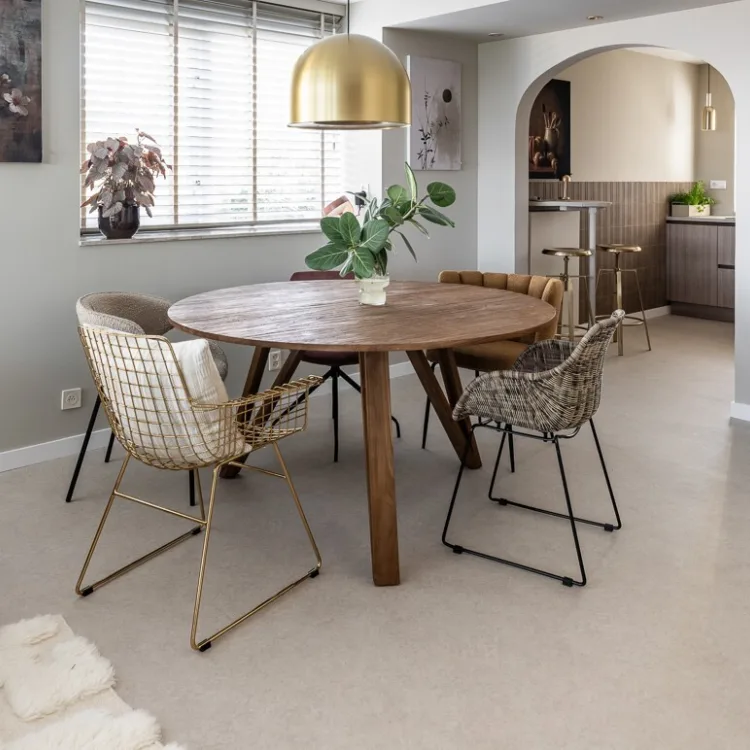 PVC-vloer in betonlook in een lichte eetkamer met ronde houten eettafel en moderne stoelen.