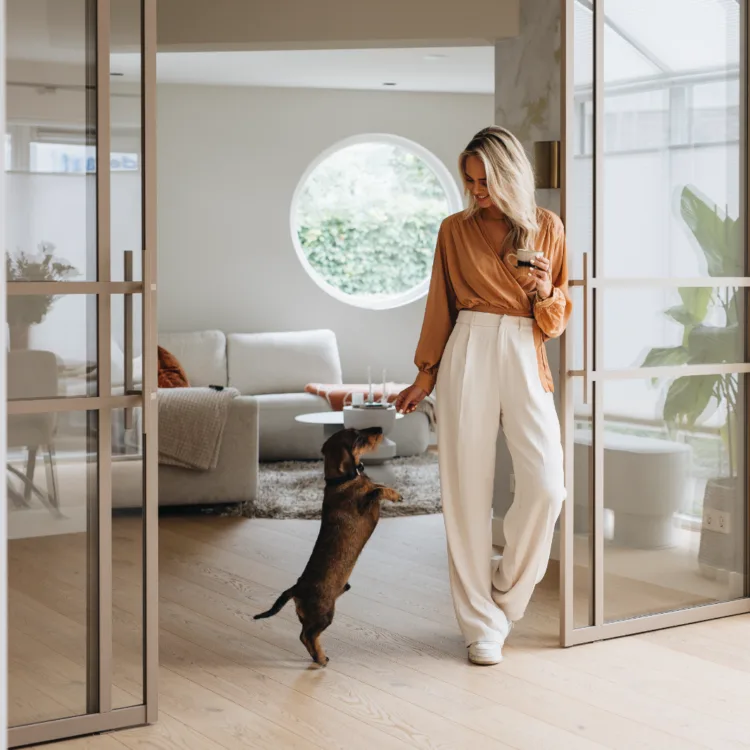 Beige stalen deuren, houten vloer in woonkamer met vrouw en hond
