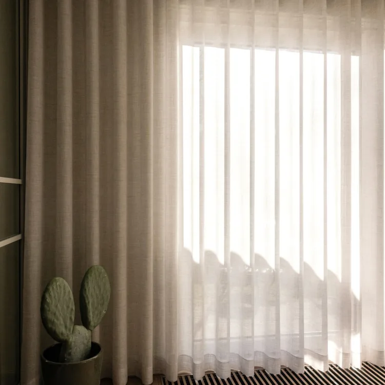 Lichtdoorlatende inbetween gordijnen gecombineerd met beige overgordijnen.